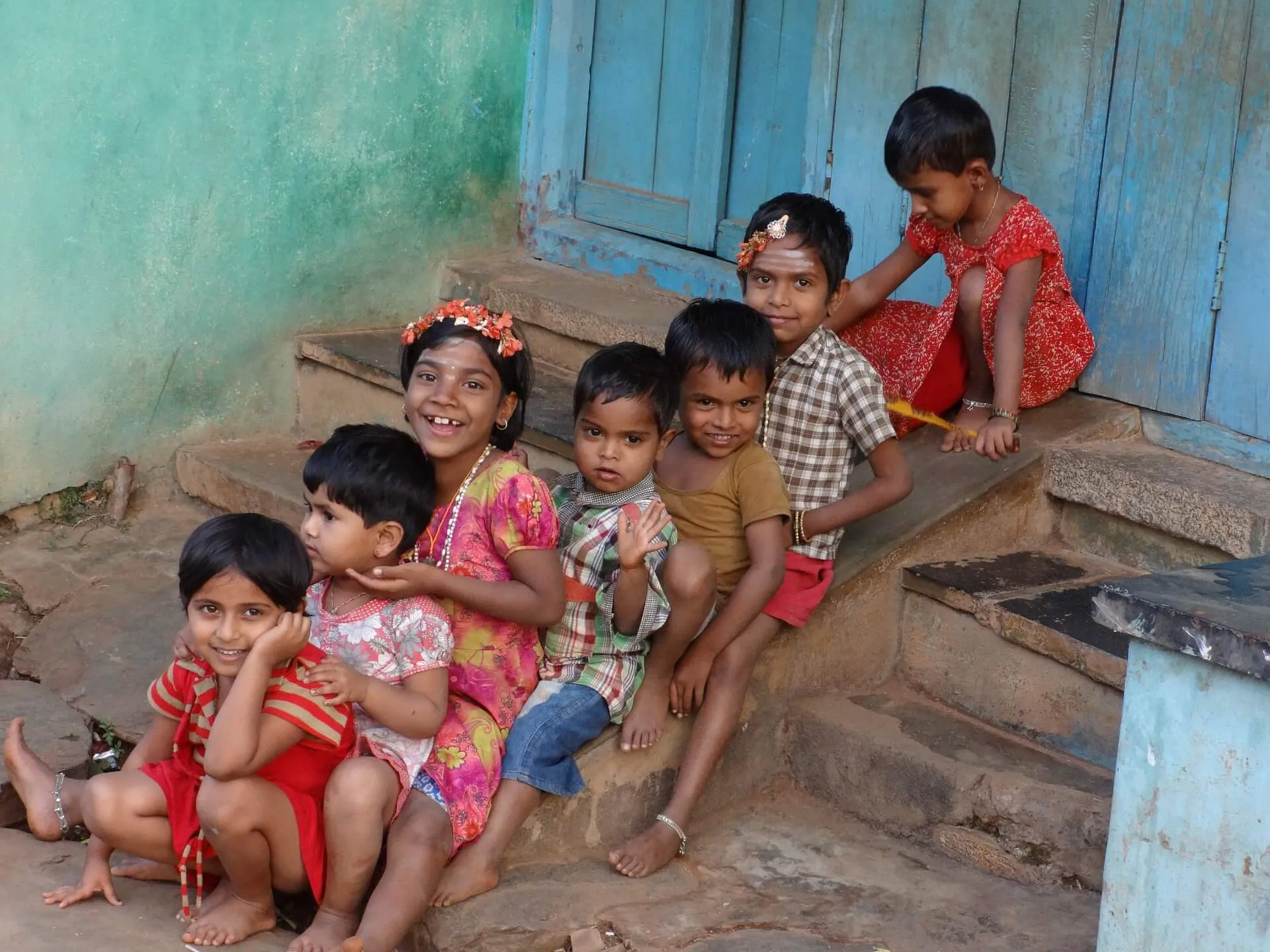 Children sitting together on the steps of a house.