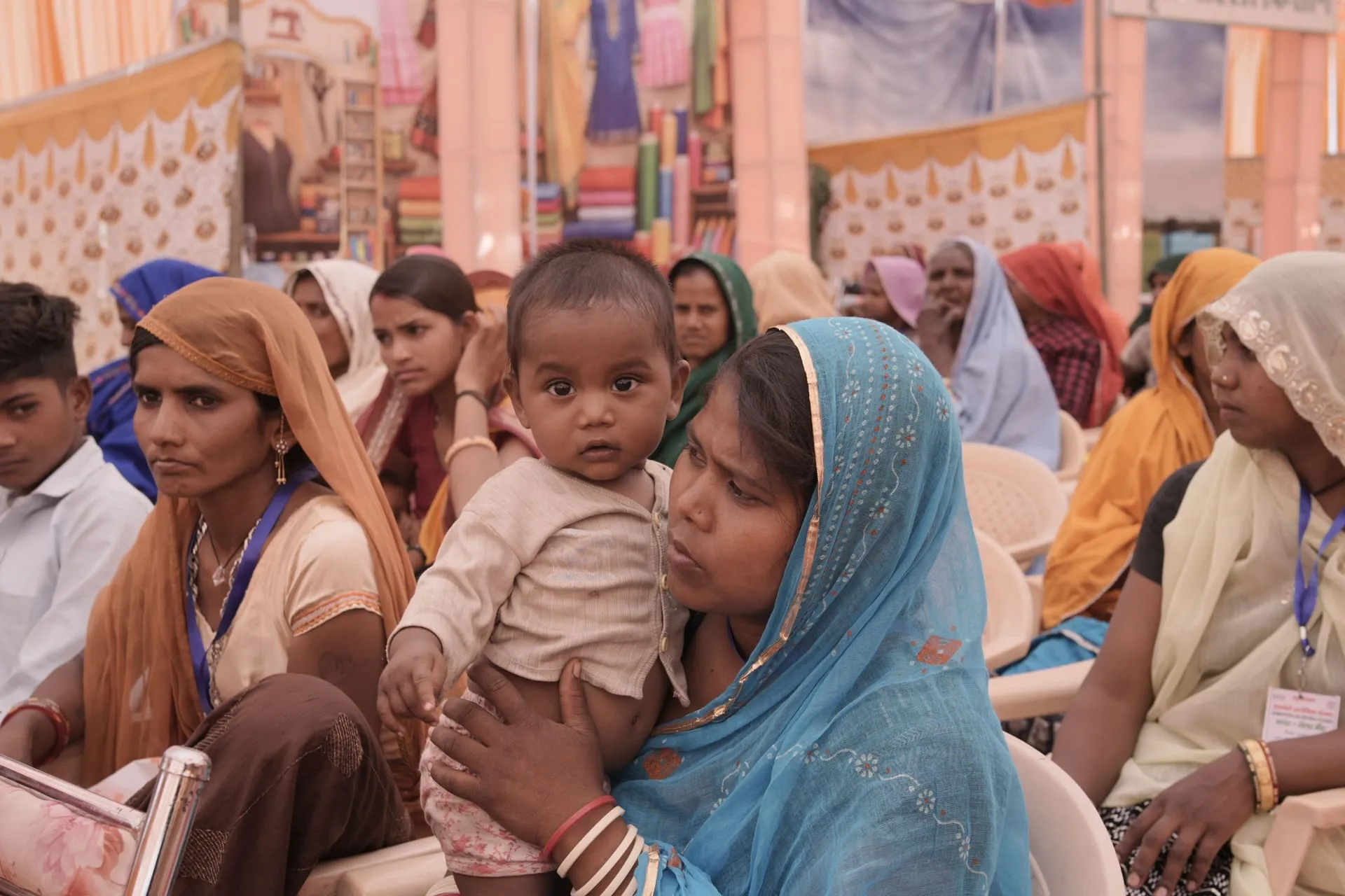 A mother holding her baby among women at a community gathering.