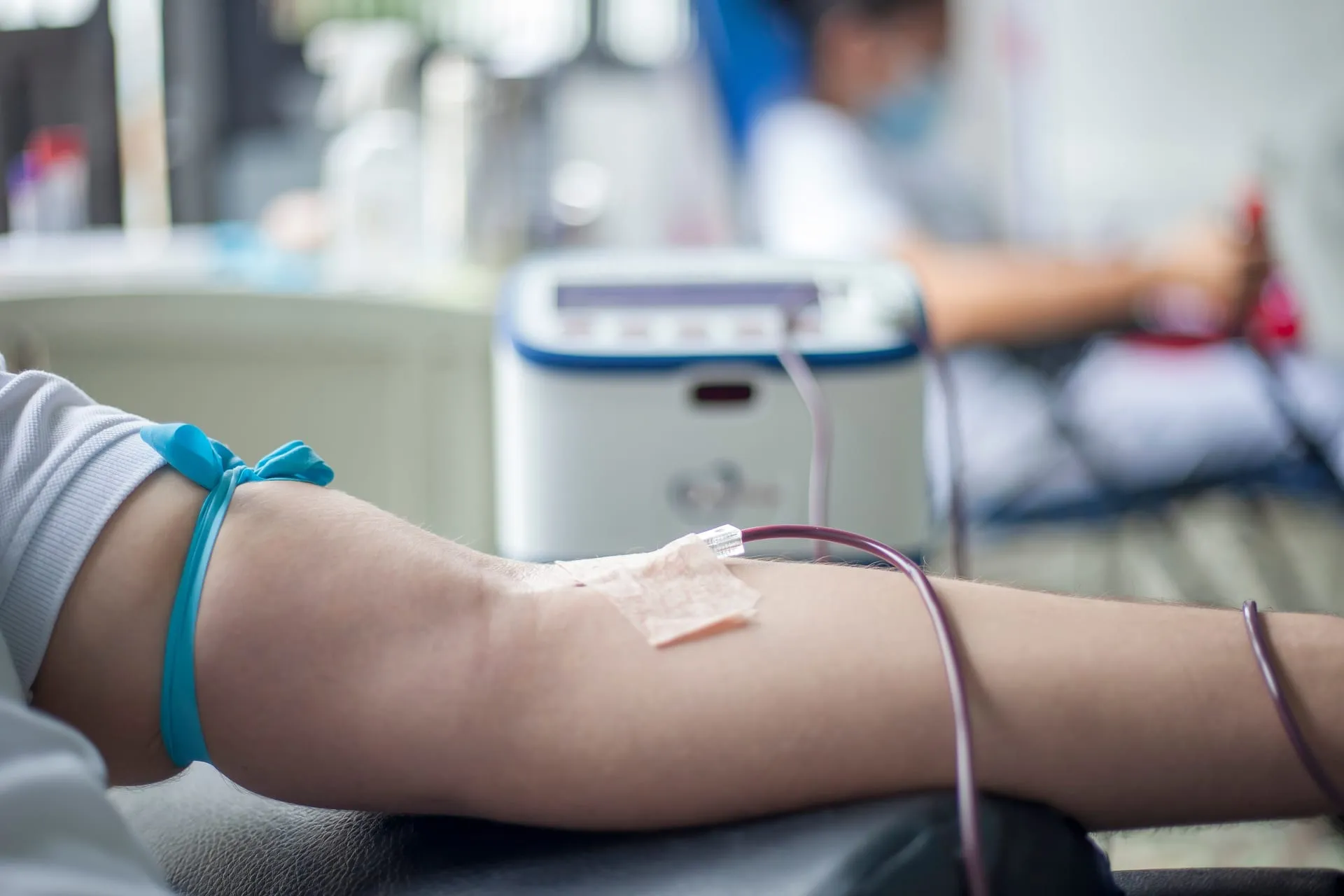 A donor’s arm with a tourniquet and line during a blood donation.
