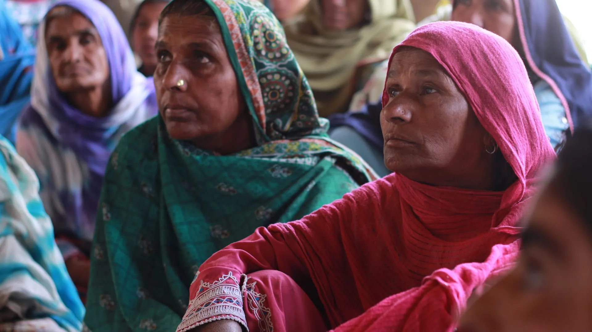 Women sitting together, listening during a community session.