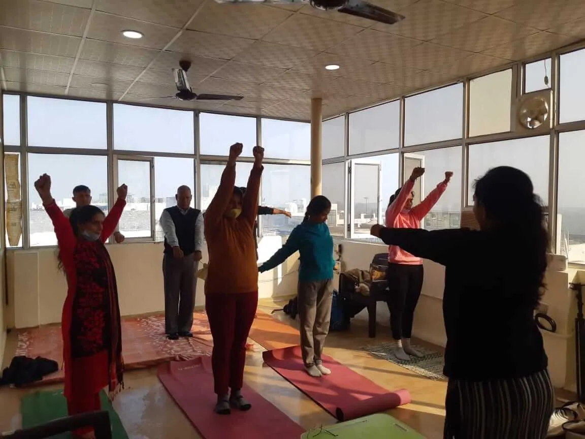 A TPNF group session with arms raised in a sunlit hall.