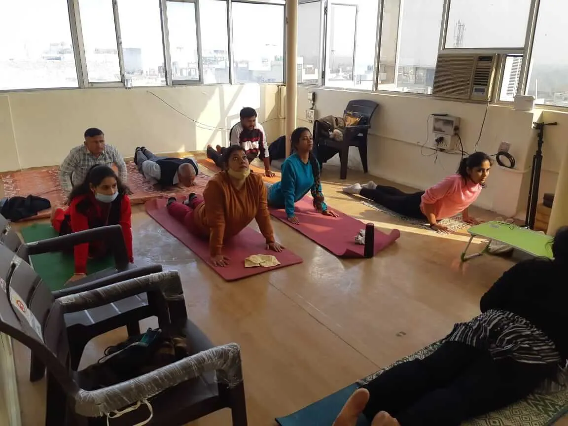 A class on yoga mats, several participants arching upward into cobra pose.