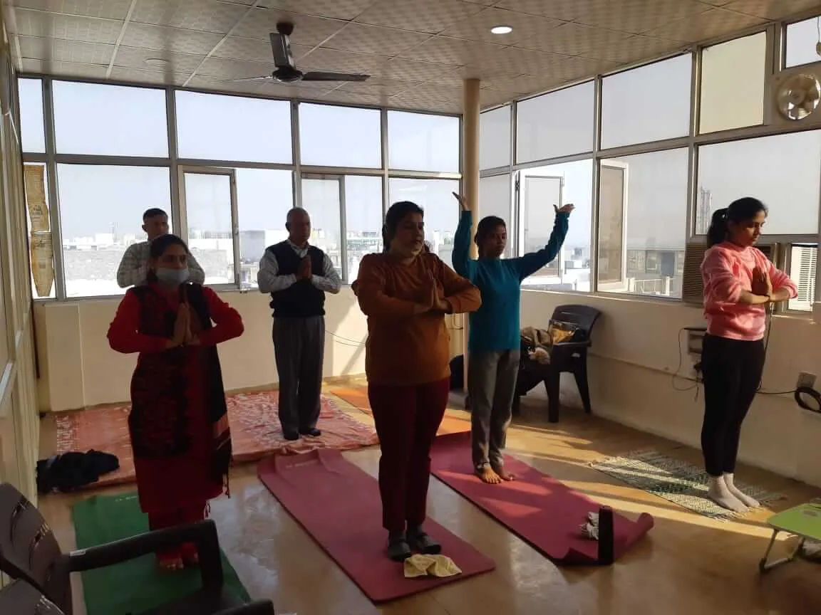 Participants standing on their mats with palms pressed together at the chest.