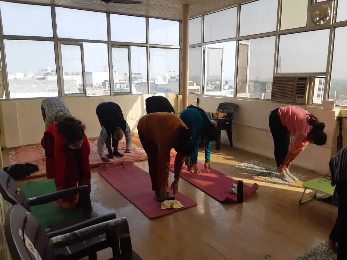 Participants bending forward over their mats in a standing forward fold.